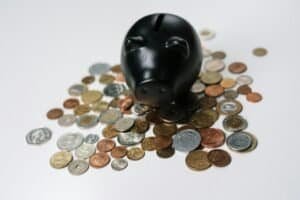 person saving coins in piggy bank showing how to save money fast on a low income