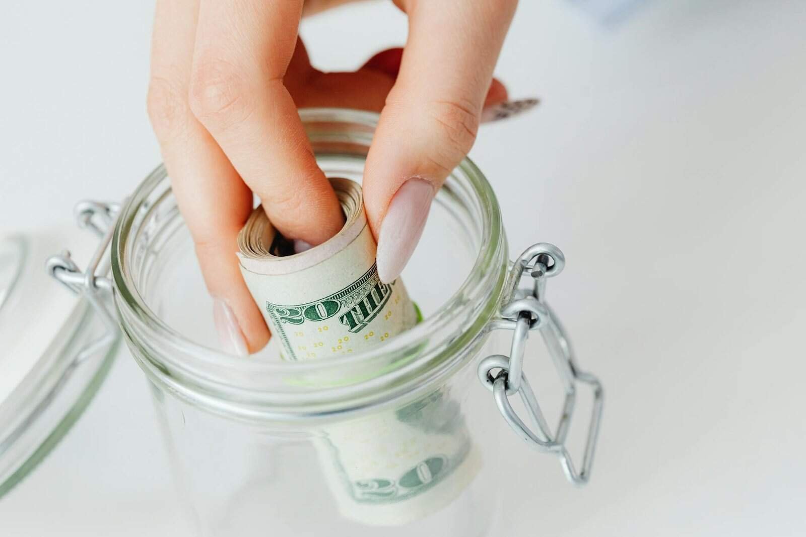 Glass jar filled with emergency fund savings money and coins on wooden table